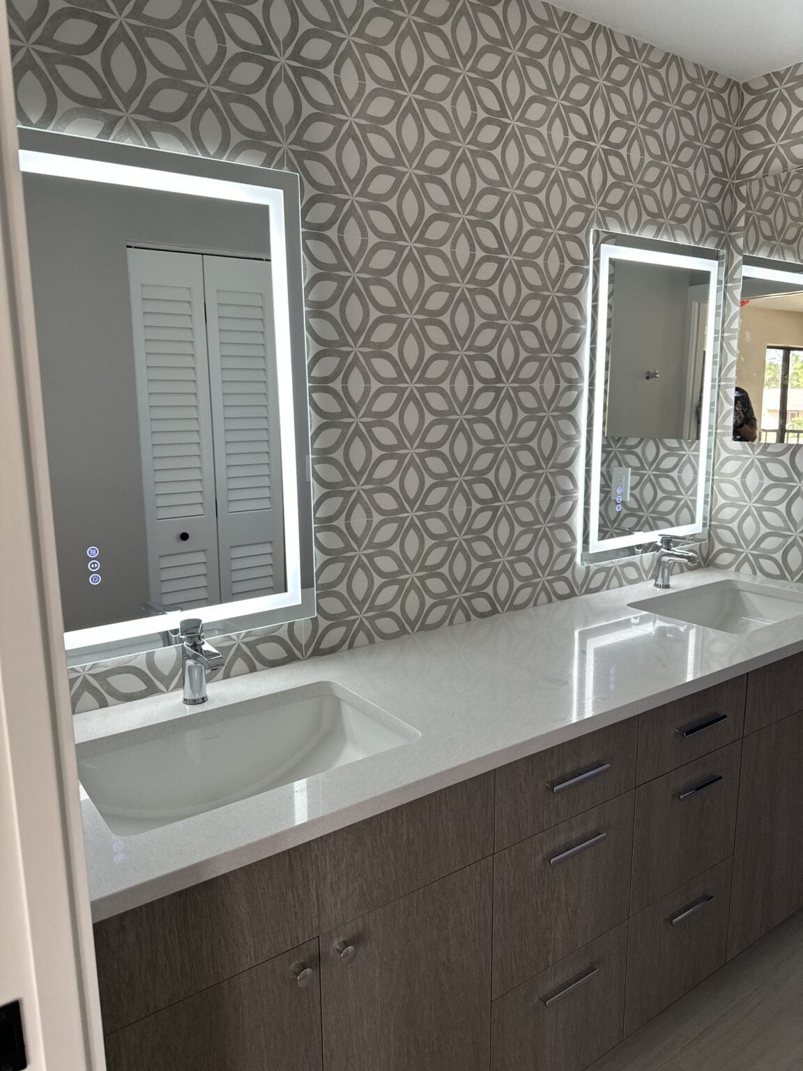 Remodeled bathroom with a double vanity and lighted mirrors