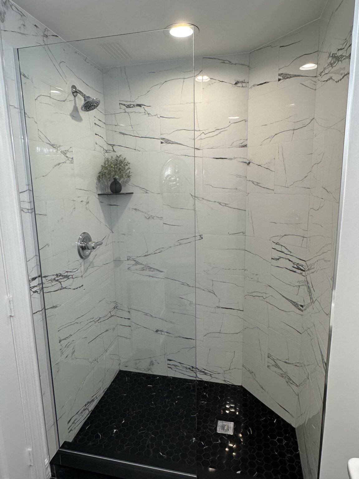 Marble tiled shower with built-in corner shelves