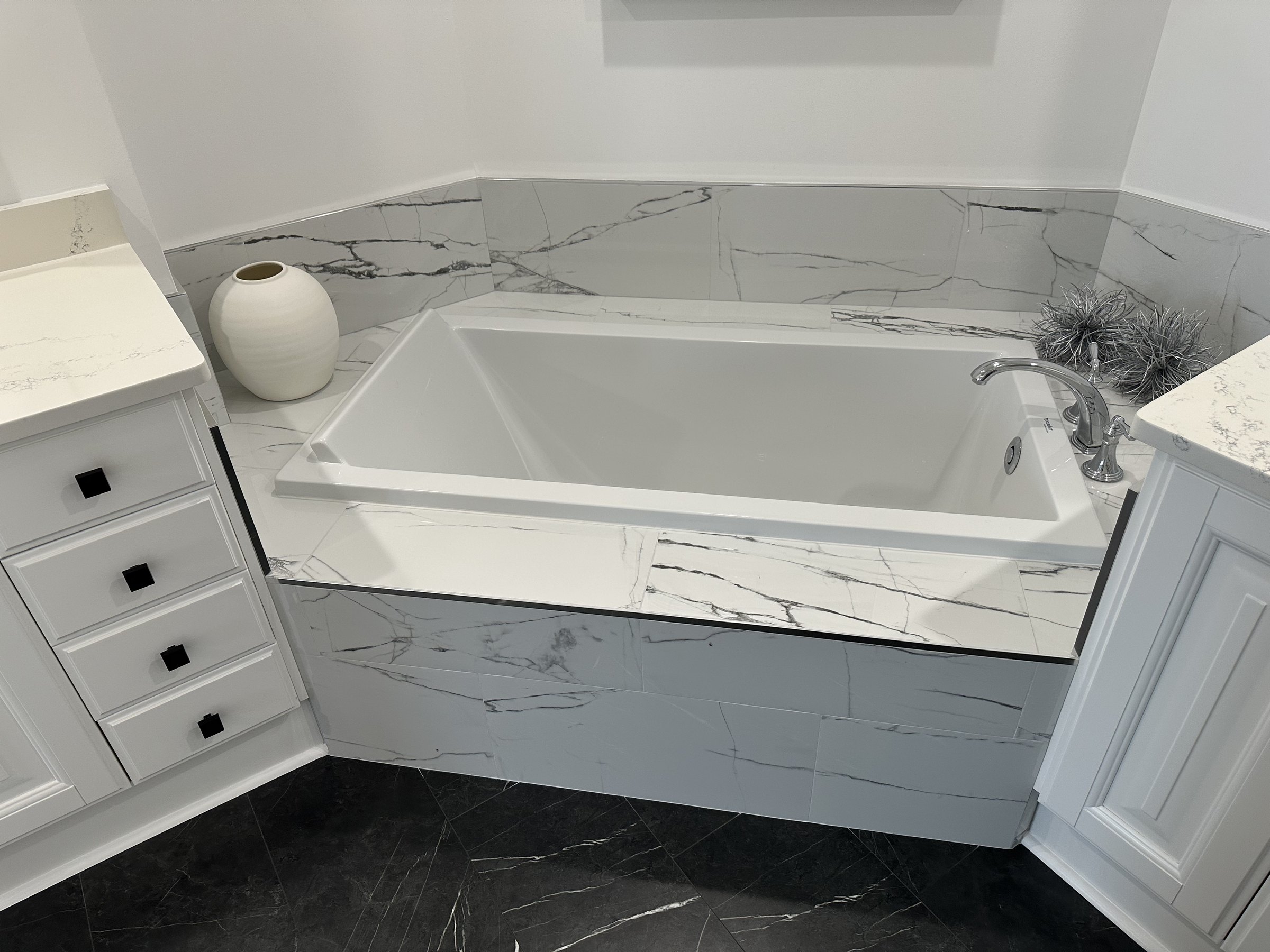 Remodeled primary bathroom with a freestanding soaking tub and marble surround