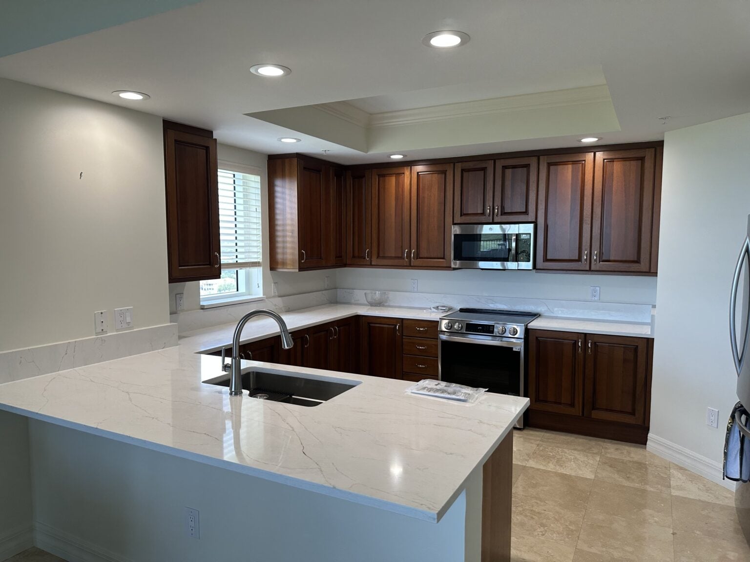 Remodeled kitchen with dark wood cabinetry and white quartz countertops